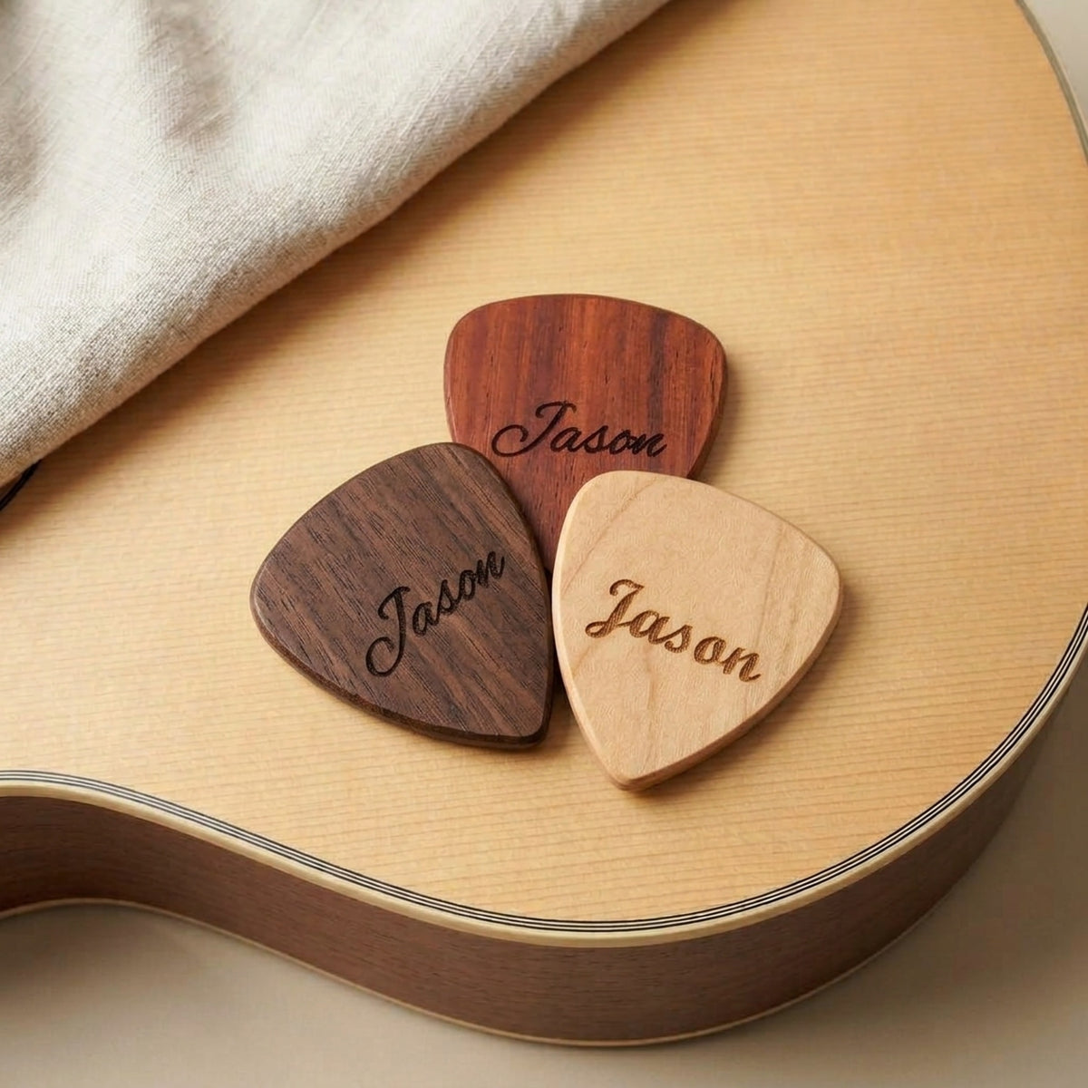Engraved wooden guitar picks resting on an acoustic guitar