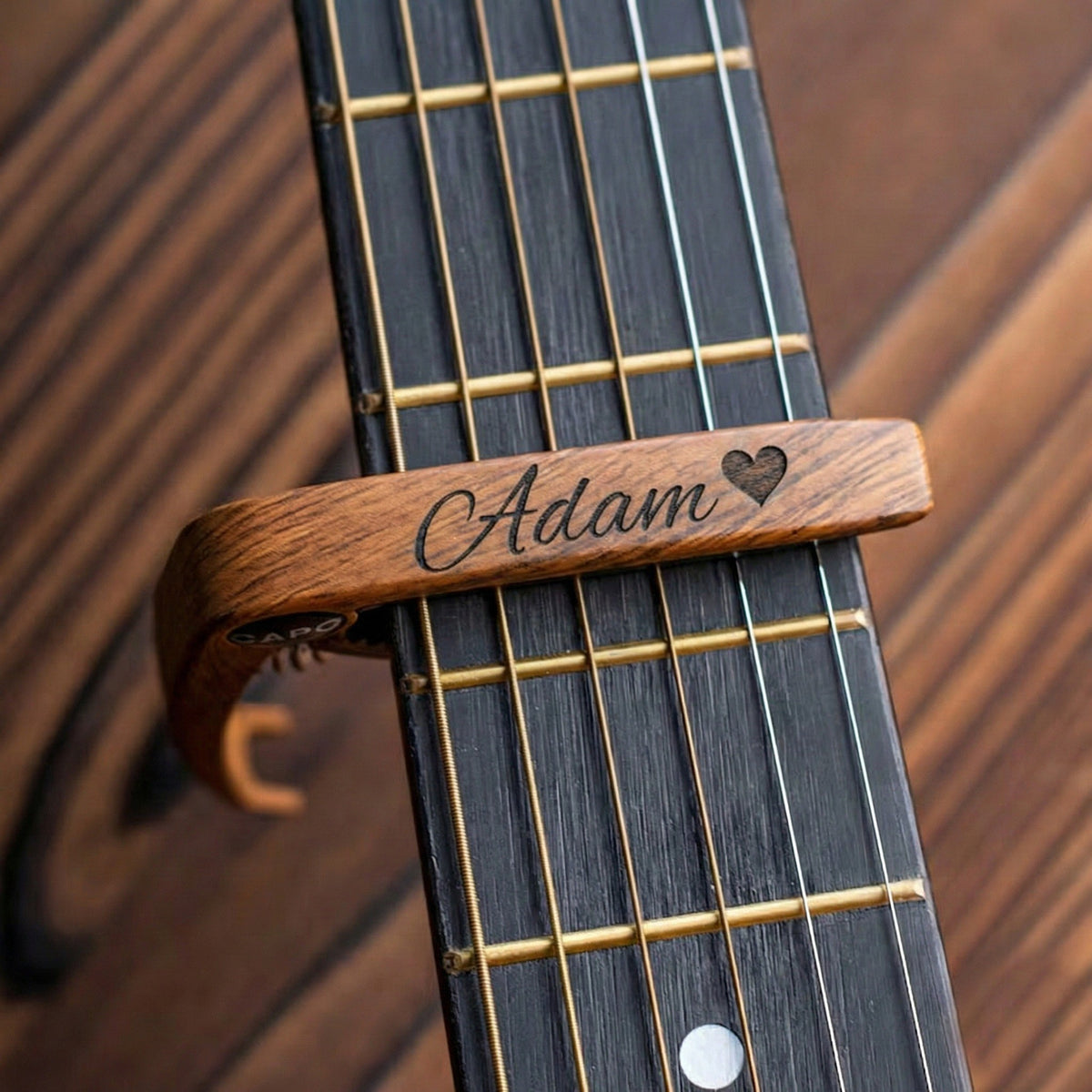 Dark wood guitar capo engraved with a name and heart