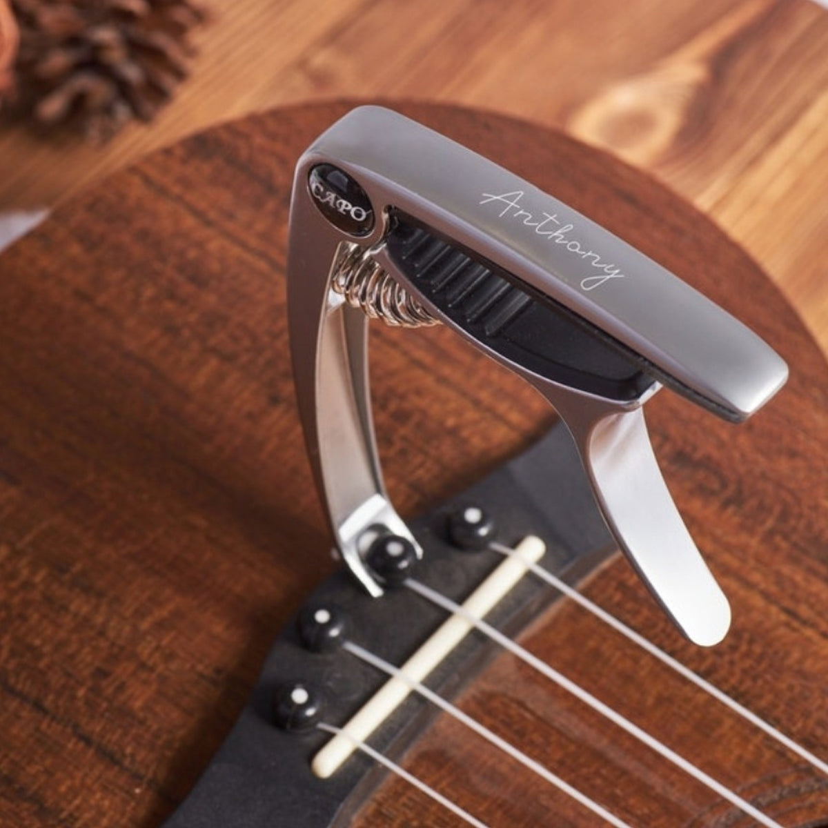 Silver engraved guitar capo clamped on a guitar neck