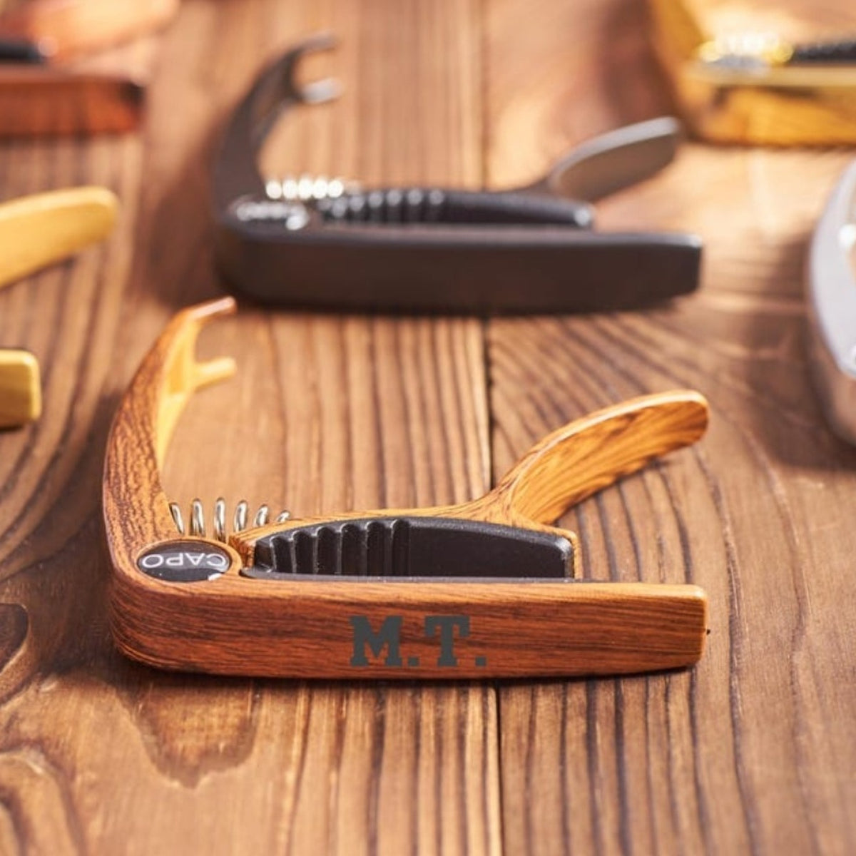 Engraved wood finish and black guitar capos on a wooden table