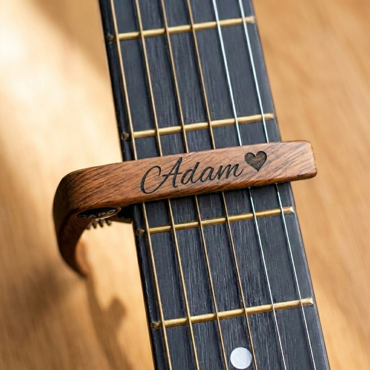 Engraved wooden capo clamped on a guitar neck